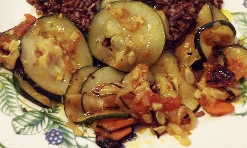 La foto muestra hortalizas salteadas a la plancha acompañadas de arroz rojo.