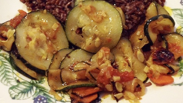 La foto muestra hortalizas salteadas a la plancha acompañadas de arroz rojo.