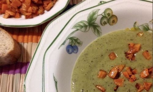 La foto muestra una crema de calabacín adornada con trocitos de zanahoria.