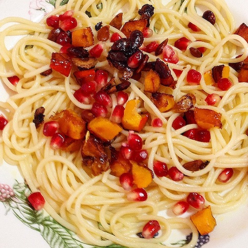 La foto muestra un plato de espagueti servido con un salteado de clabaza Hokkaido y semillas de granada.