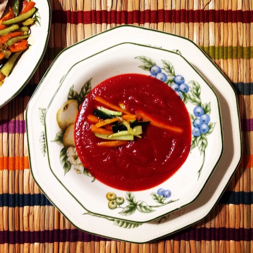 La foto muestra una crema Borsch, de remolacha como ingrediente principal. Servida con hortalizas cortadas en tiras.