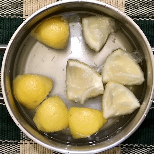 La foto muestra una tartera con agua y la corteza de un limón troceada en cuartos.