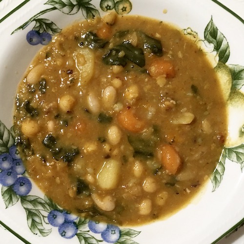 La foto muestra un potaje, un guiso de verduras y legumbres, servido en el plato.